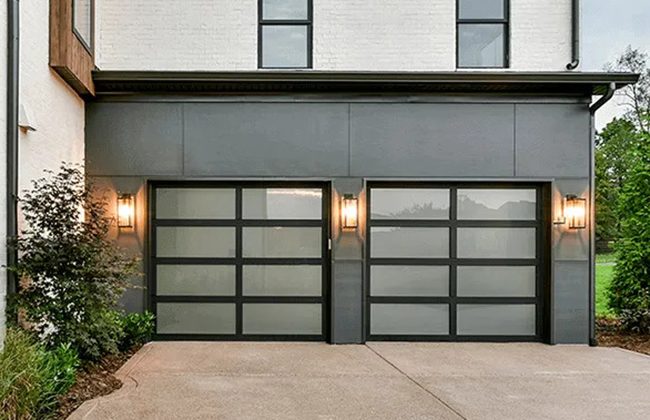 Modern house exterior with dual frosted glass garage doors, featuring sleek design and warm outdoor lighting.