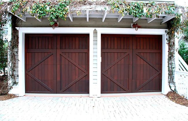 Double wooden garage doors with ivy embellishments, providing a rustic and elegant home entrance.