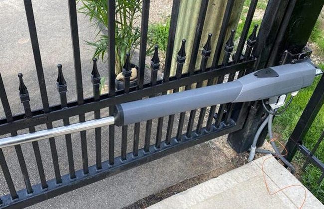Automatic gate arm mechanism on a metal fence, ensuring secure entry for residential or commercial properties.