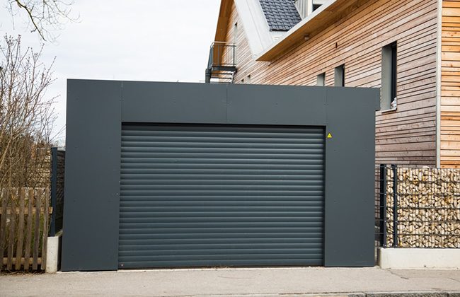 Modern black garage door with house wooden siding exterior in residential area.