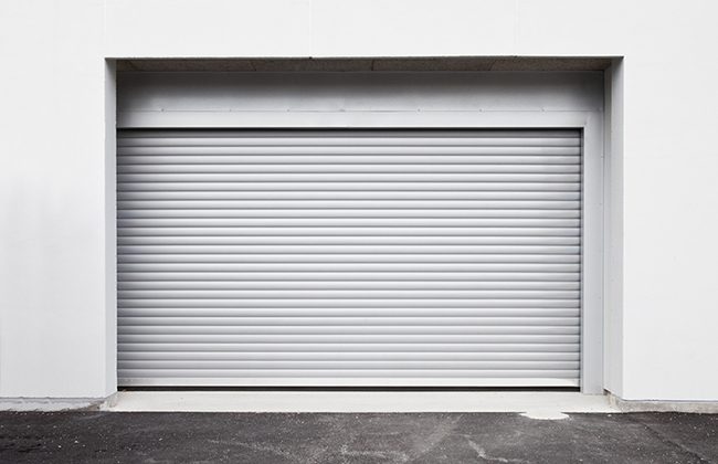 Closed grey roller garage door on a modern white building exterior.