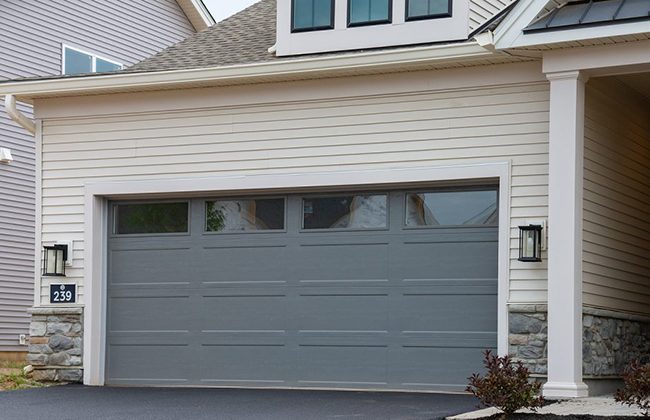 Modern suburban home with a closed gray garage door and stone accents.
